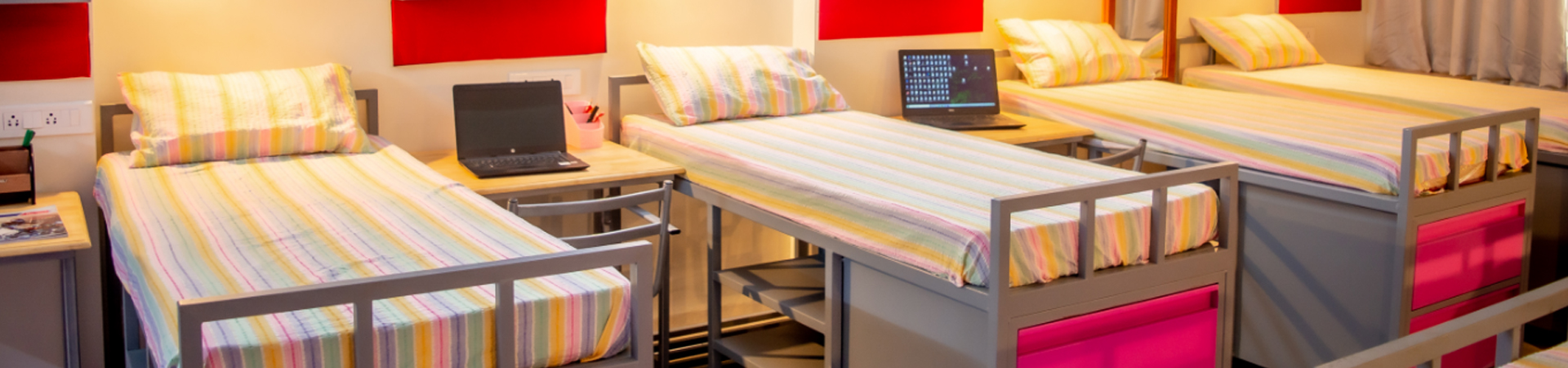 Multi-share girls hostel room with beds at Rani Meyyammai Hostel