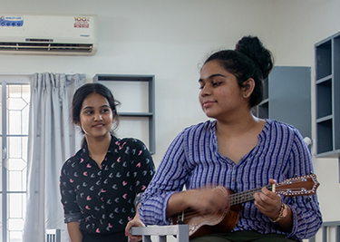 Two people indoors, ukulele playing
